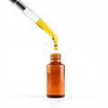 Dropper releasing a golden oil droplet